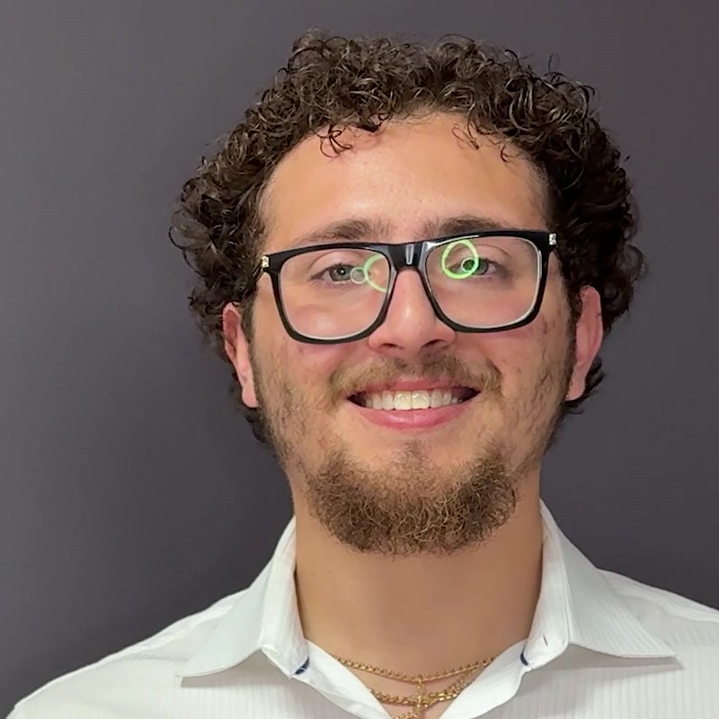 Drew, smiling, in glasses and a white button-down shirt